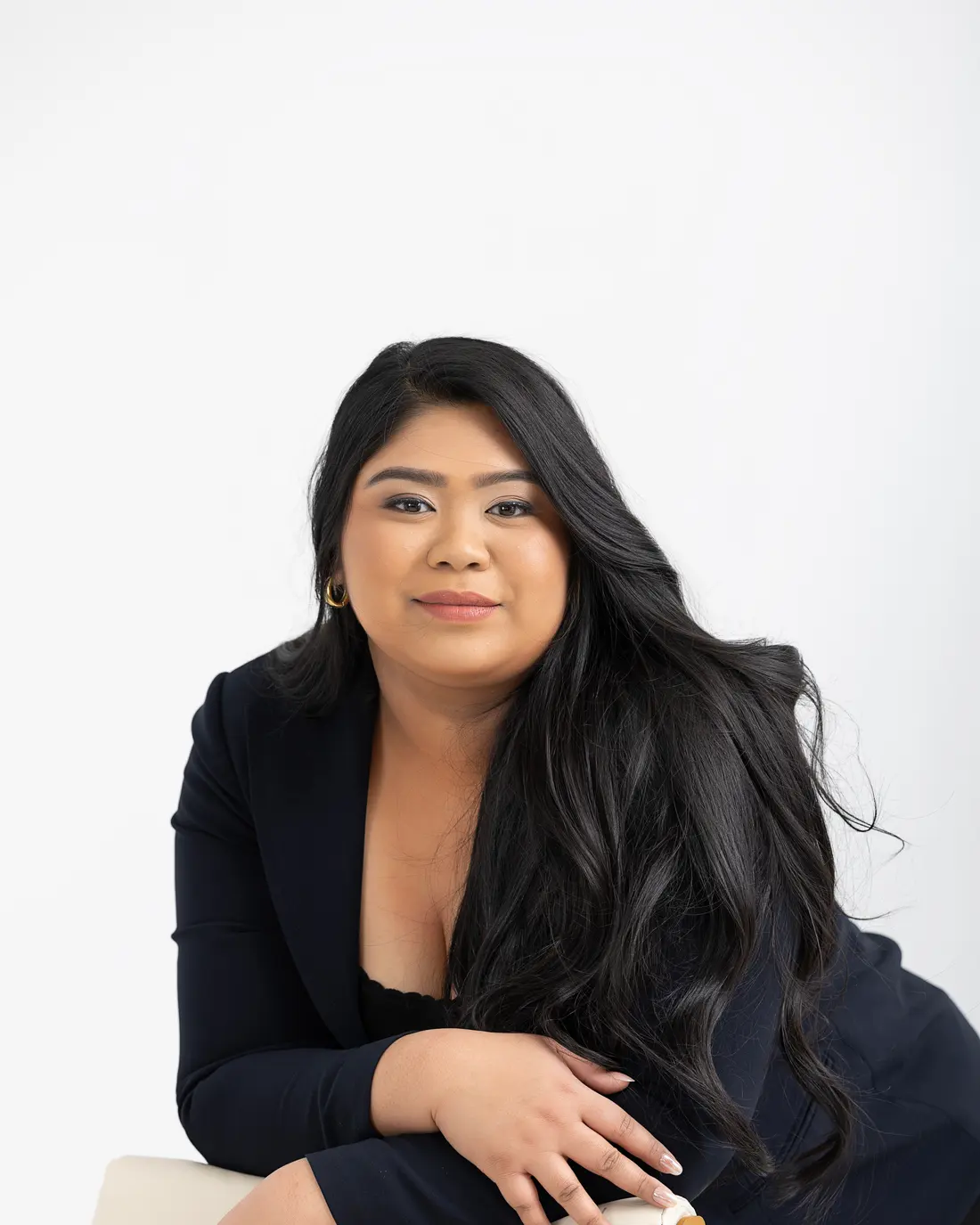 Chelsea Javier, residential real estate broker in Montreal, seated and smiling in a navy blazer