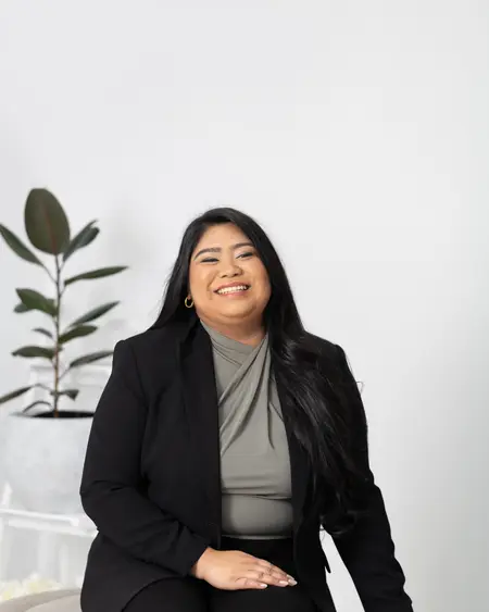 Chelsea Javier seated, laughing, in a black blazer
